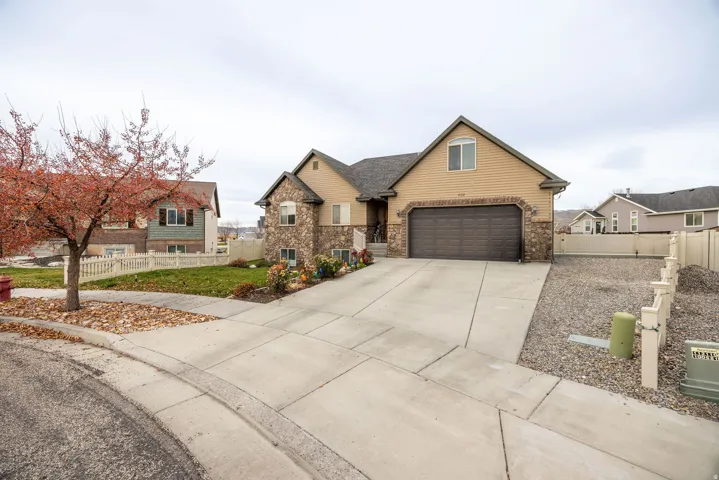 View of front facade with driveway, stone siding, and a garage