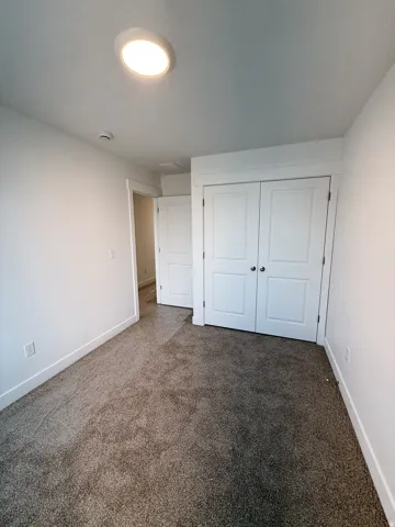 Unfurnished bedroom with dark carpet and a closet