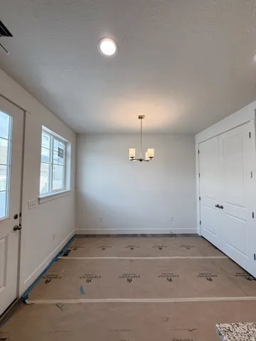 Unfurnished dining area with a textured ceiling and hanging lights