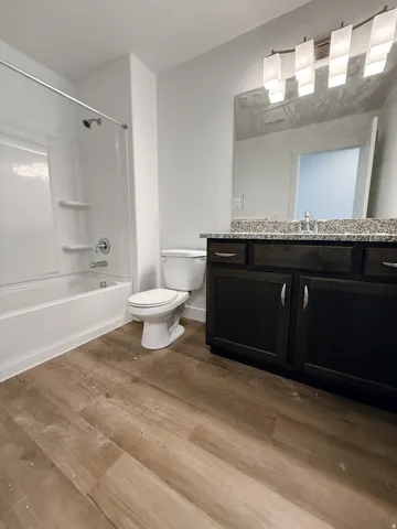 Bathroom with vanity,  shower combination, and dark wood-style floors