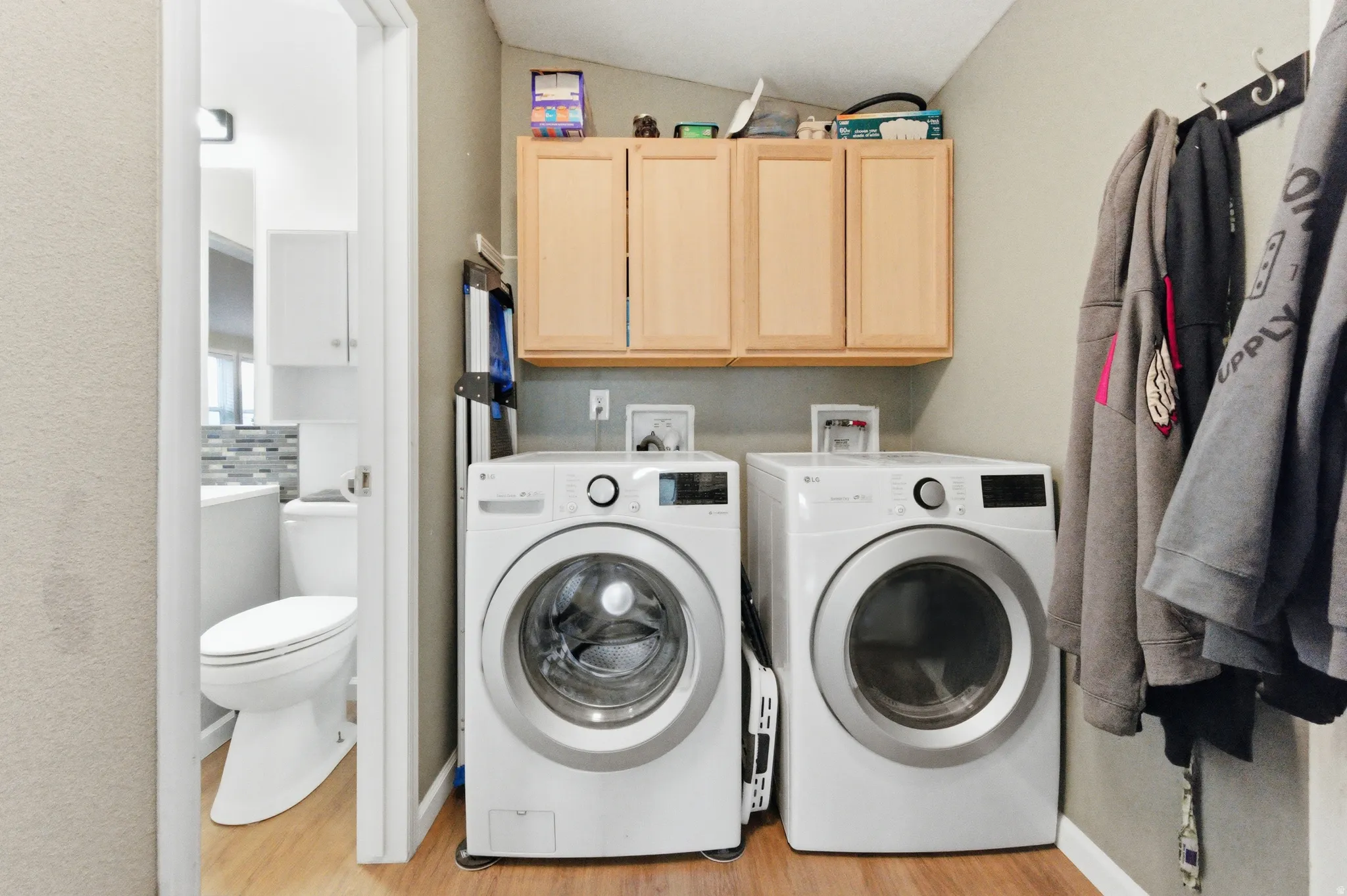 Laundry area with cabinet space, washer and dryer, light wood-style flooring, and lofted ceiling