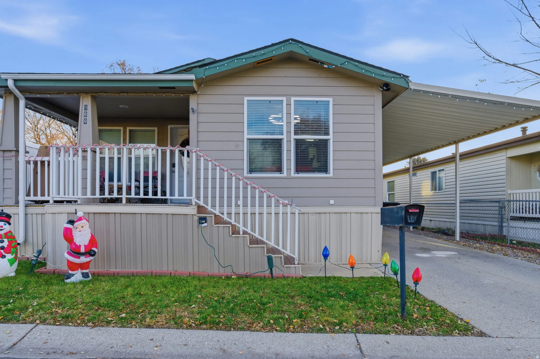 Manufactured / mobile home with stairway, driveway, an attached carport, and a front lawn