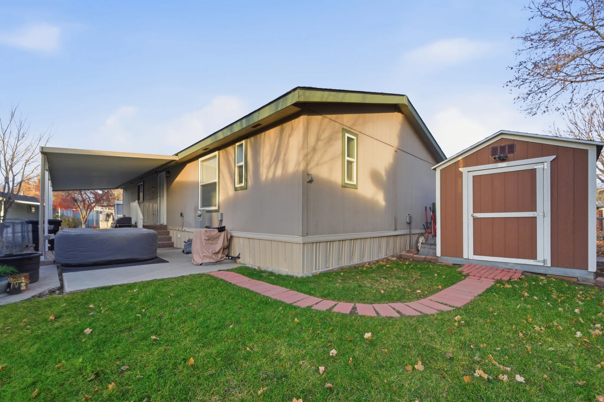 Rear view of house with a lawn, a storage shed, and a patio