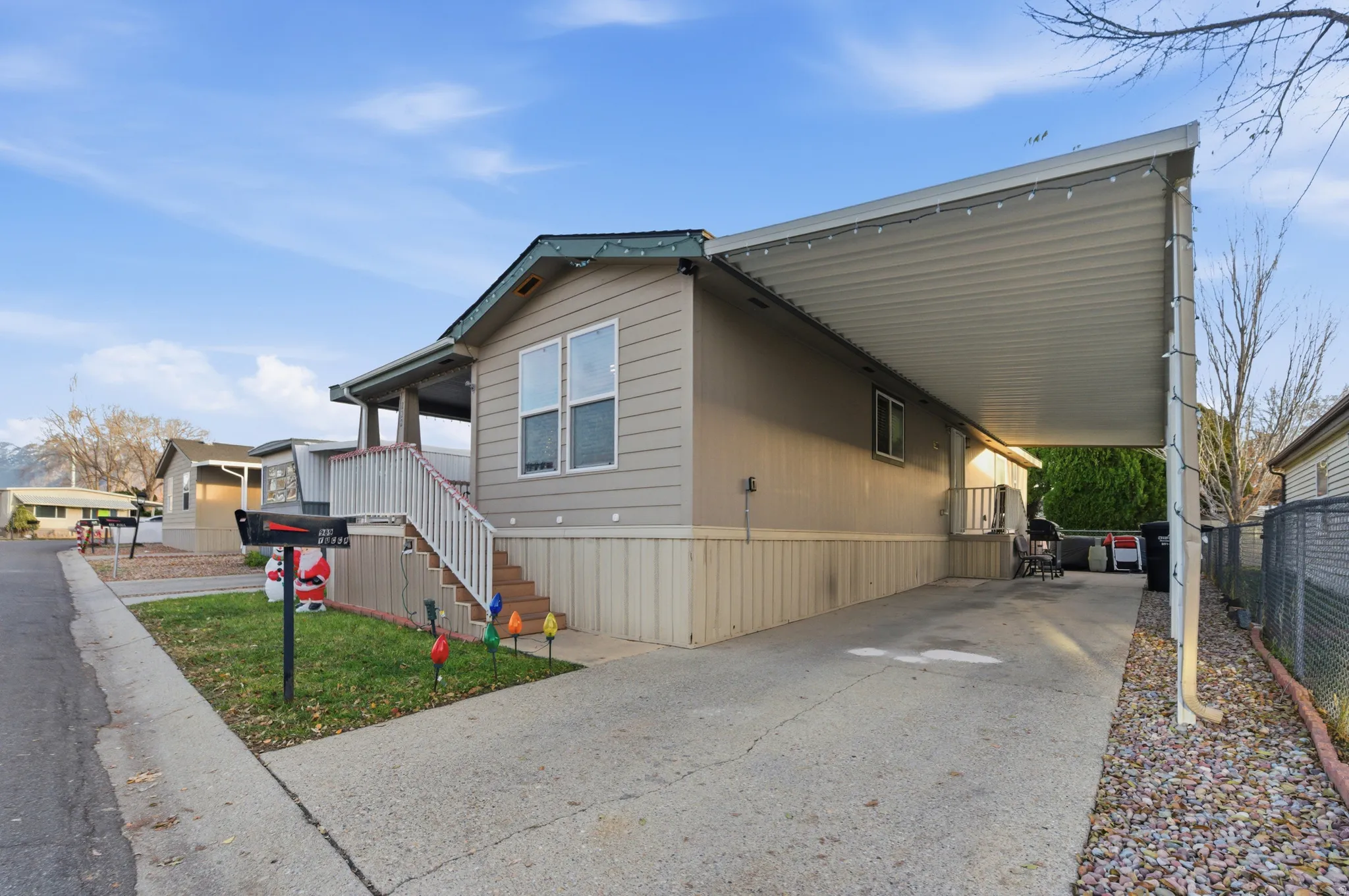 View of side of home with an attached carport, concrete driveway, and stairway