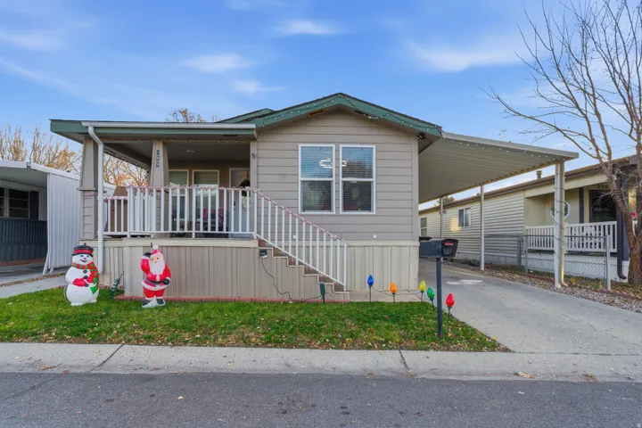 Manufactured / mobile home with driveway, stairs, an attached carport, a porch, and a front yard