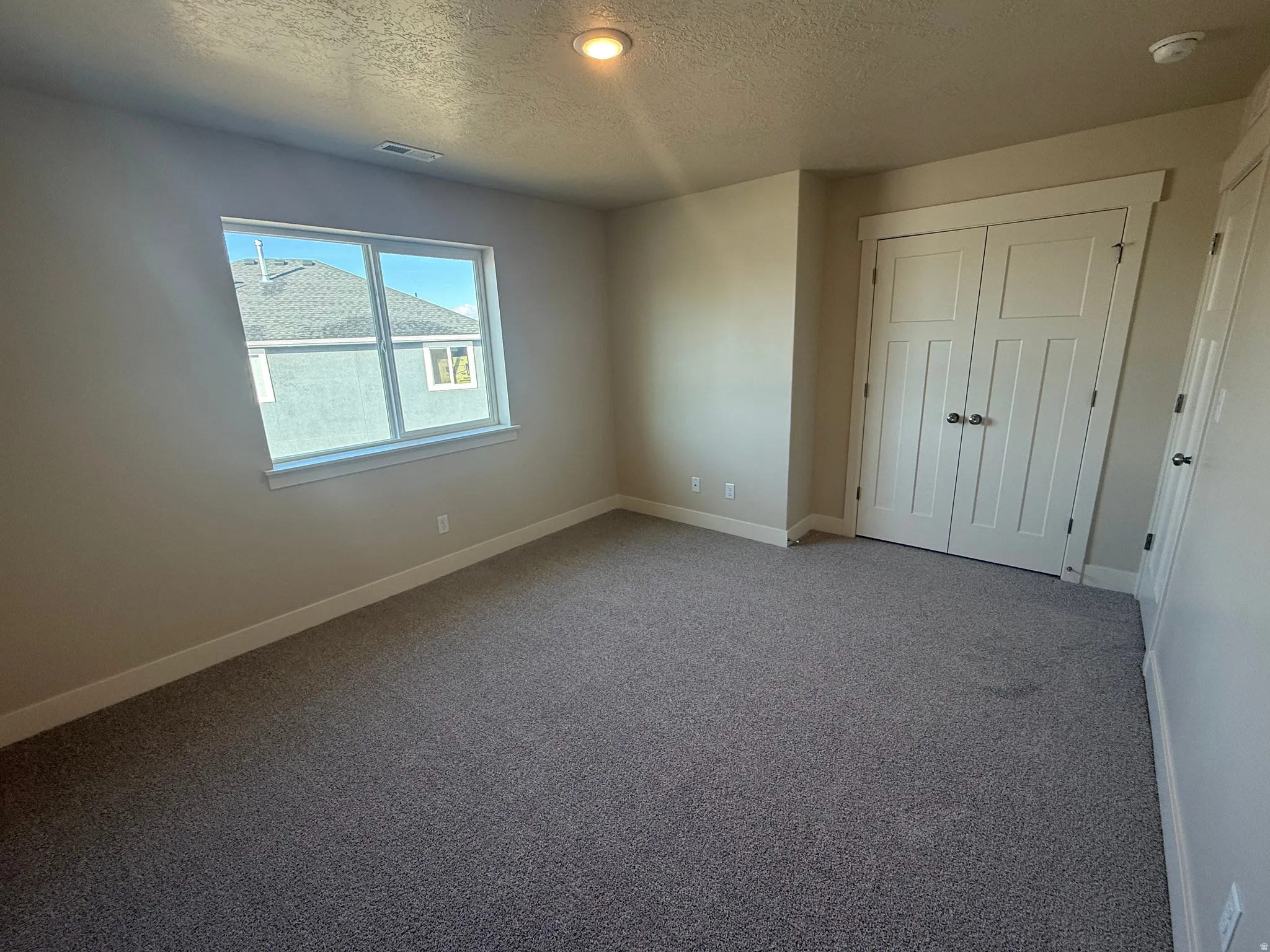Unfurnished bedroom featuring a textured ceiling, carpet floors, and a closet