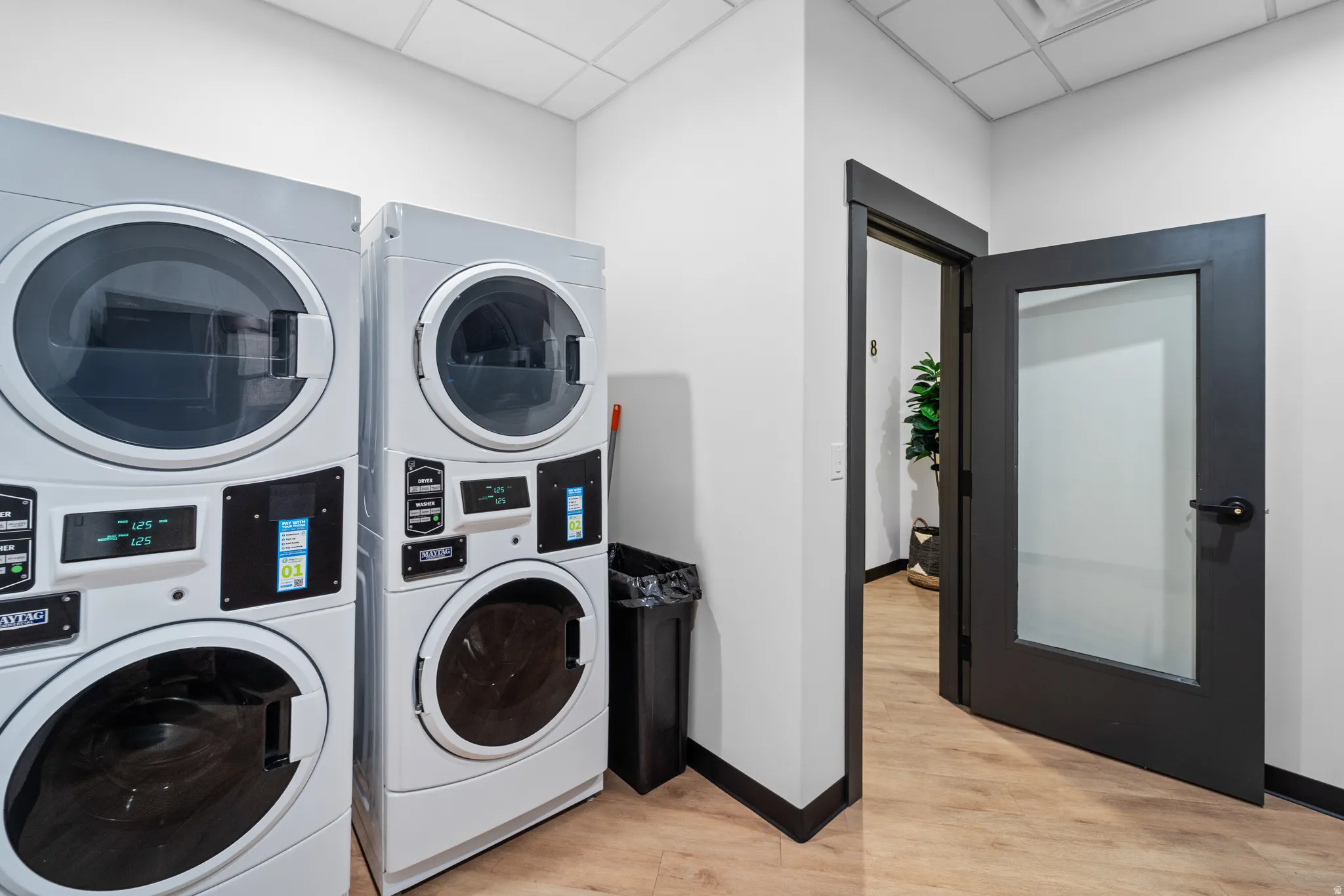 Washroom with stacked washer and clothes dryer and a paneled ceiling