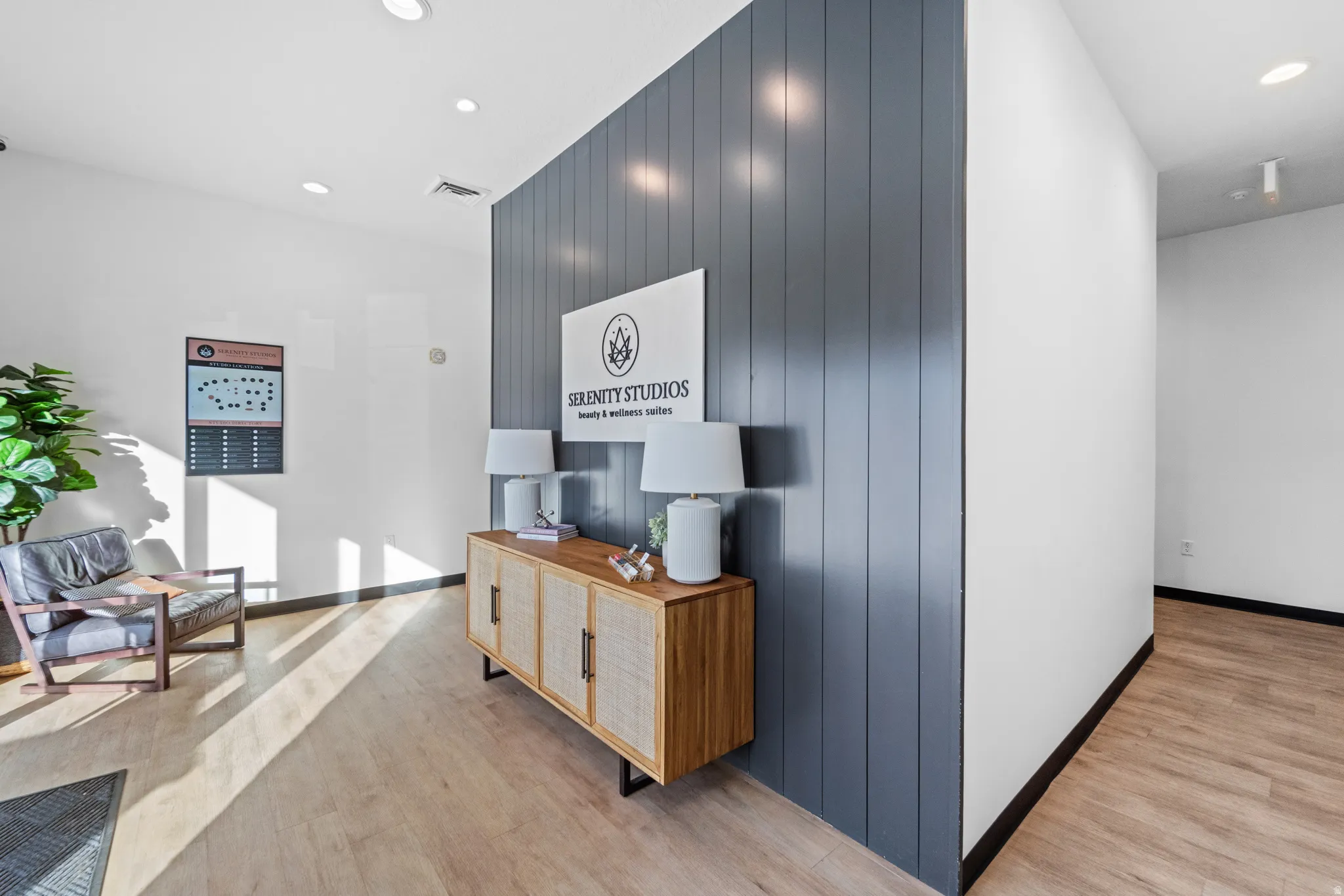 Hallway with recessed lighting, light wood finished floors, an accent wall, and wood walls