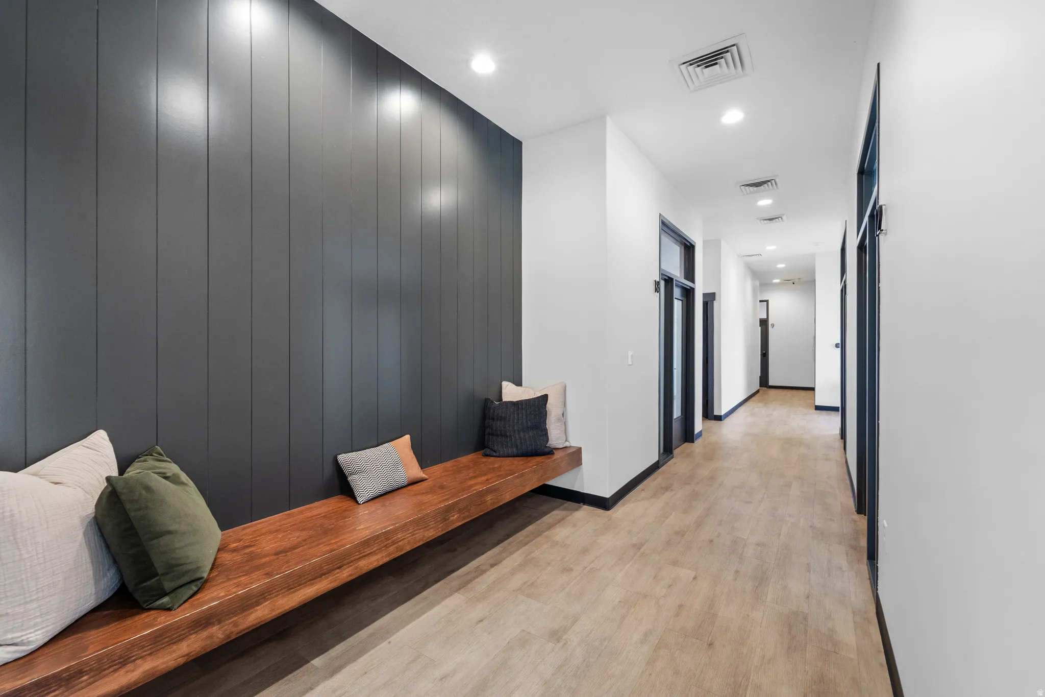Hall with recessed lighting, light wood finished floors, and wood walls