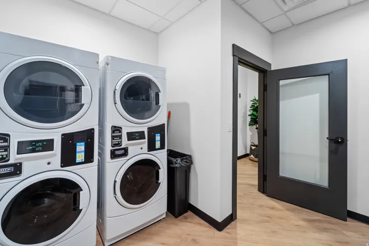 Washroom with stacked washer and clothes dryer and a paneled ceiling