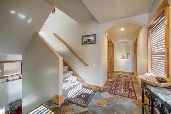 Hallway with stone tile floors, arched walkways, and stairway