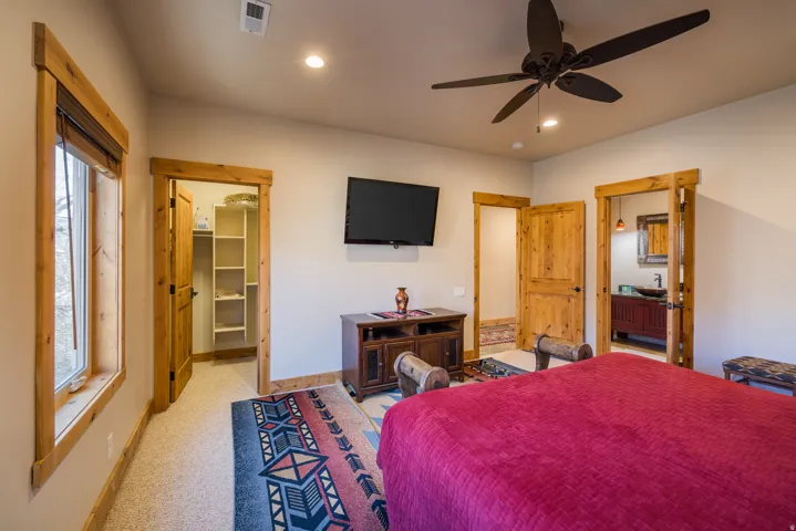 Bedroom with a spacious closet, ceiling fan, light colored carpet, and recessed lighting