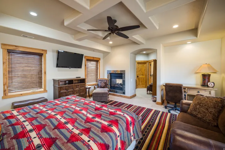 Bedroom featuring beamed ceiling, coffered ceiling, a ceiling fan, recessed lighting, and a multi sided fireplace