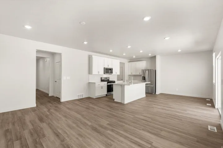 **DISLCAIMER** Exterior & Interior packages may vary.Kitchen with open floor plan, stainless steel appliances, a center island with sink, white cabinetry, and recessed lighting