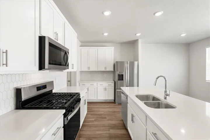 **DISLCAIMER** Exterior & Interior packages may vary.Kitchen with stainless steel appliances, tasteful backsplash, white cabinetry, light stone counters, and recessed lighting
