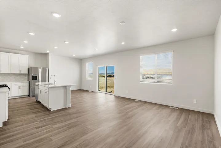 **DISLCAIMER** Exterior & Interior packages may vary.Kitchen featuring white cabinets, decorative backsplash, open floor plan, a kitchen island with sink, and light wood-type flooring