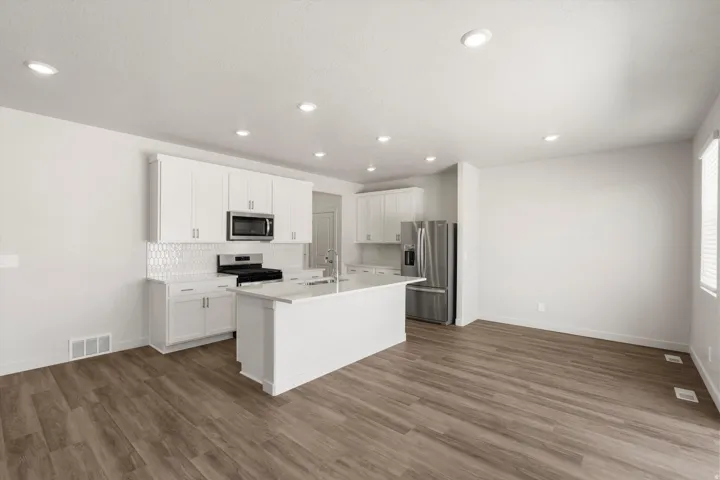 **DISLCAIMER** Exterior & Interior packages may vary.Kitchen featuring white cabinetry, appliances with stainless steel finishes, an island with sink, decorative backsplash, and dark wood-type flooring