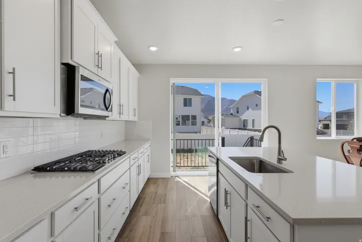 View 2 Kitchen featuring white cabinets, light stone counters, a kitchen island with sink, light wood-style floors, and recessed lighting