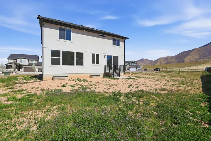 Back of house with a mountain view, stucco siding, and entry steps