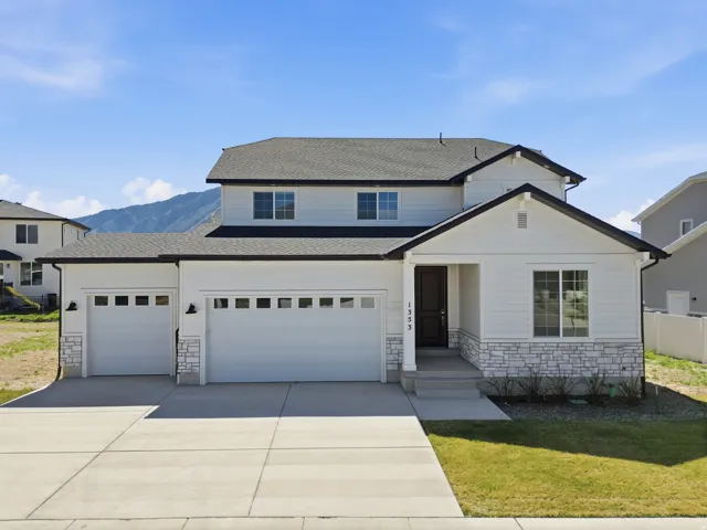 Traditional home with stone siding, roof with shingles, driveway, and an attached garage