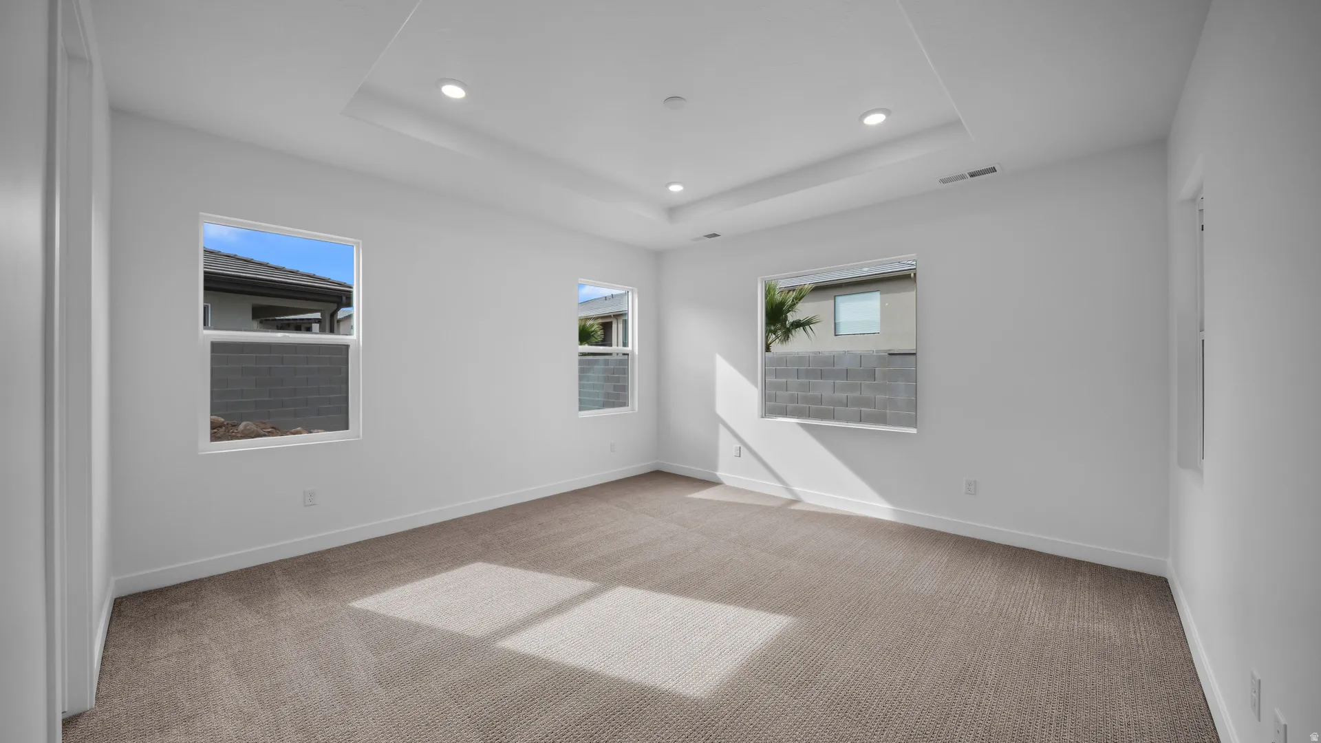 Empty room featuring light colored carpet, recessed lighting, and a raised ceiling