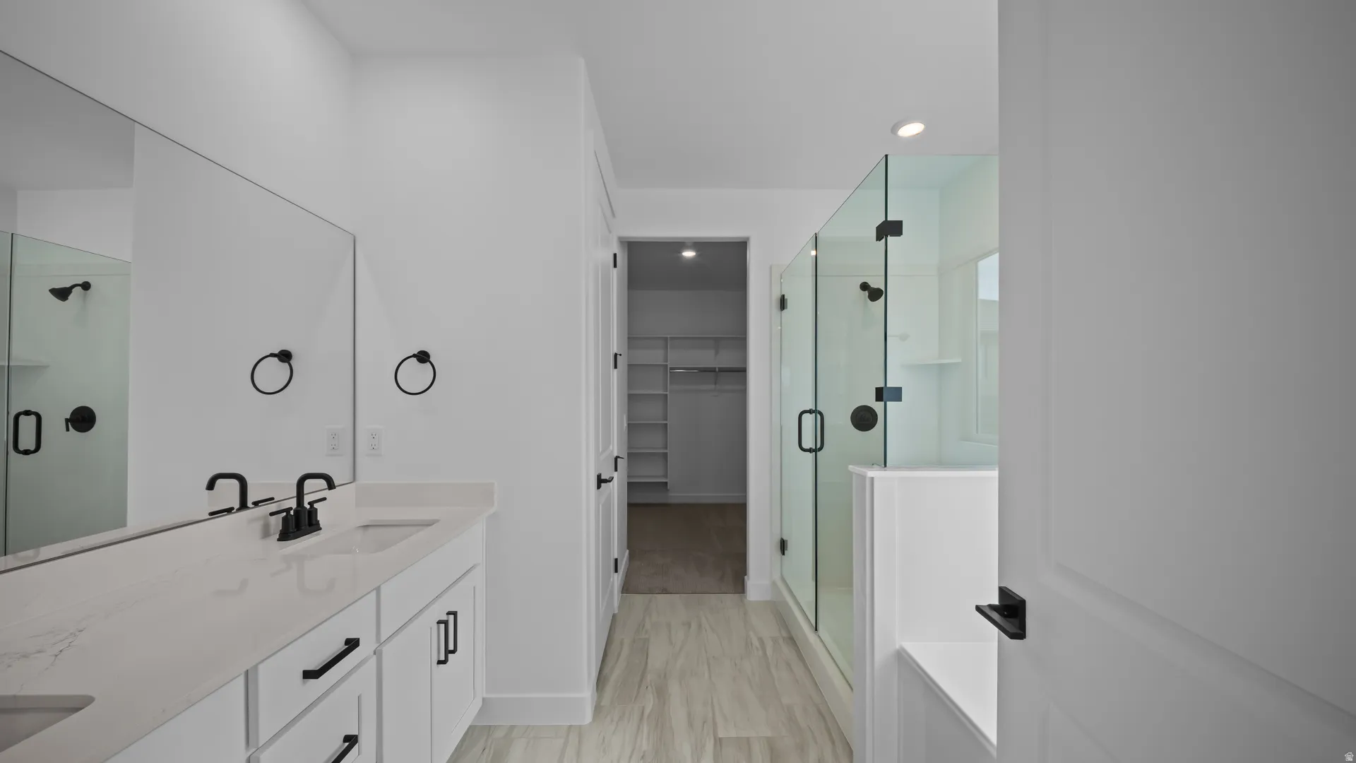 Bathroom featuring a shower stall, a spacious closet, double vanity, and recessed lighting
