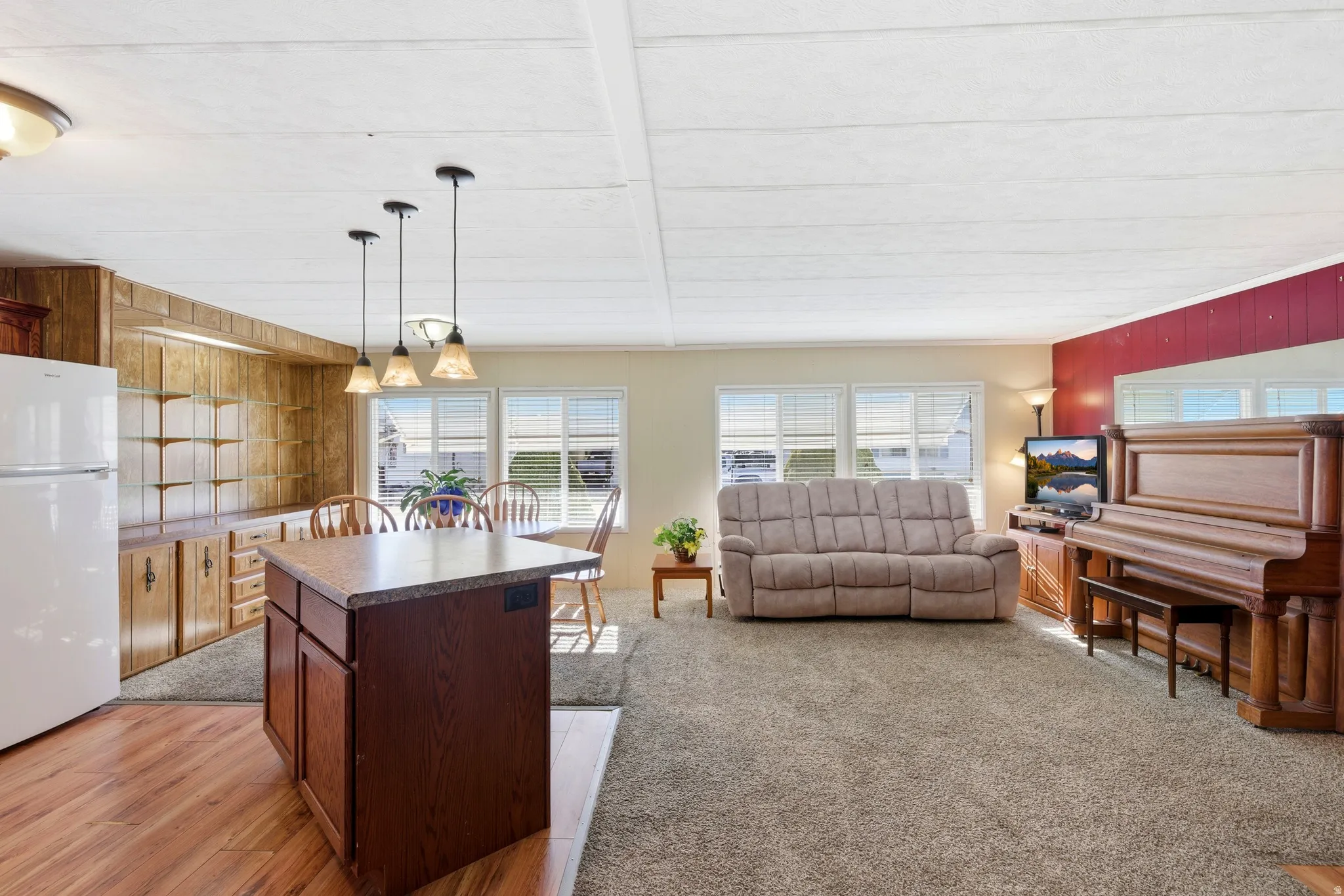 Kitchen featuring hanging light fixtures, freestanding refrigerator, open floor plan, wooden walls, and a kitchen island