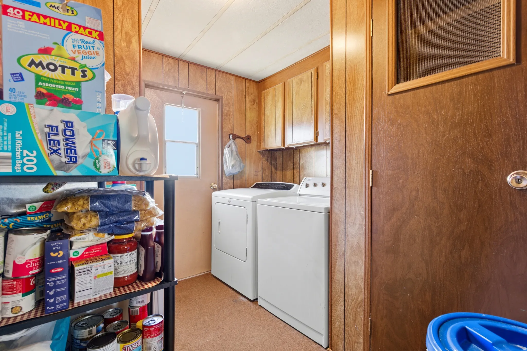Washroom featuring wooden walls, washer and dryer, and cabinet space
