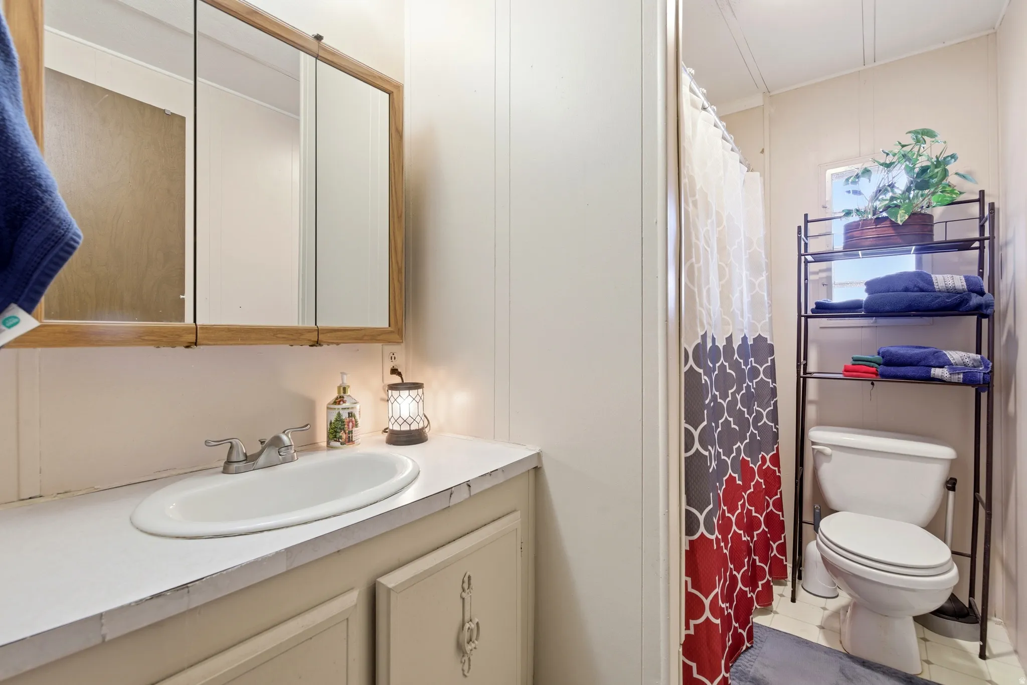 Full bathroom featuring curtained shower, vanity, a decorative wall, and tile patterned flooring