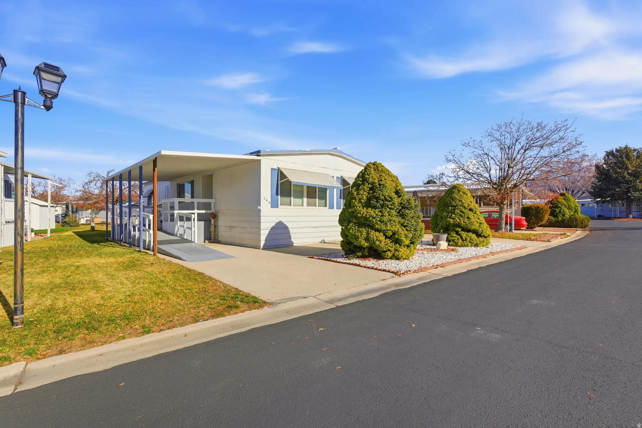 Manufactured / mobile home with a front lawn, driveway, and an attached carport
