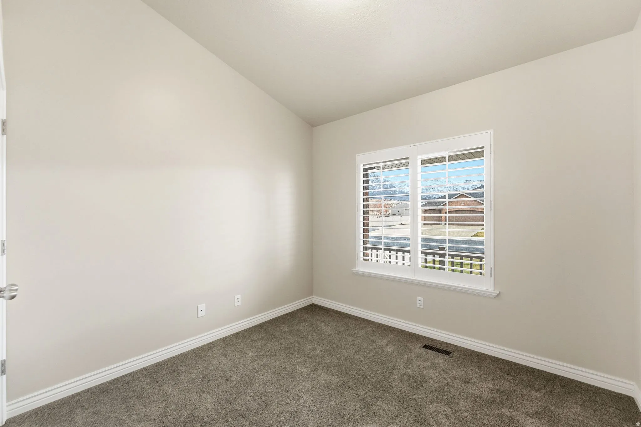 Empty room with carpet and lofted ceiling