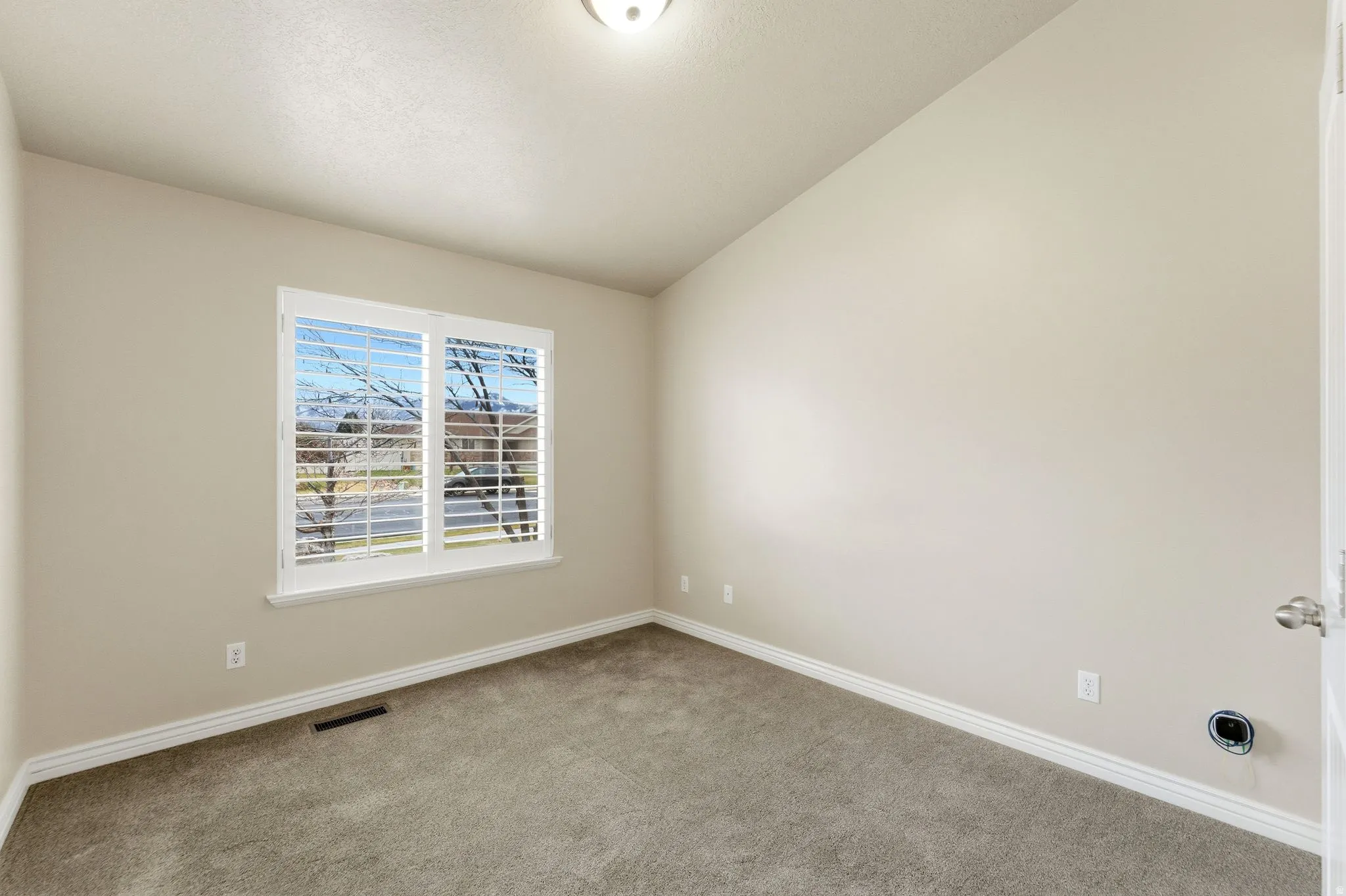 Carpeted empty room featuring baseboards and lofted ceiling