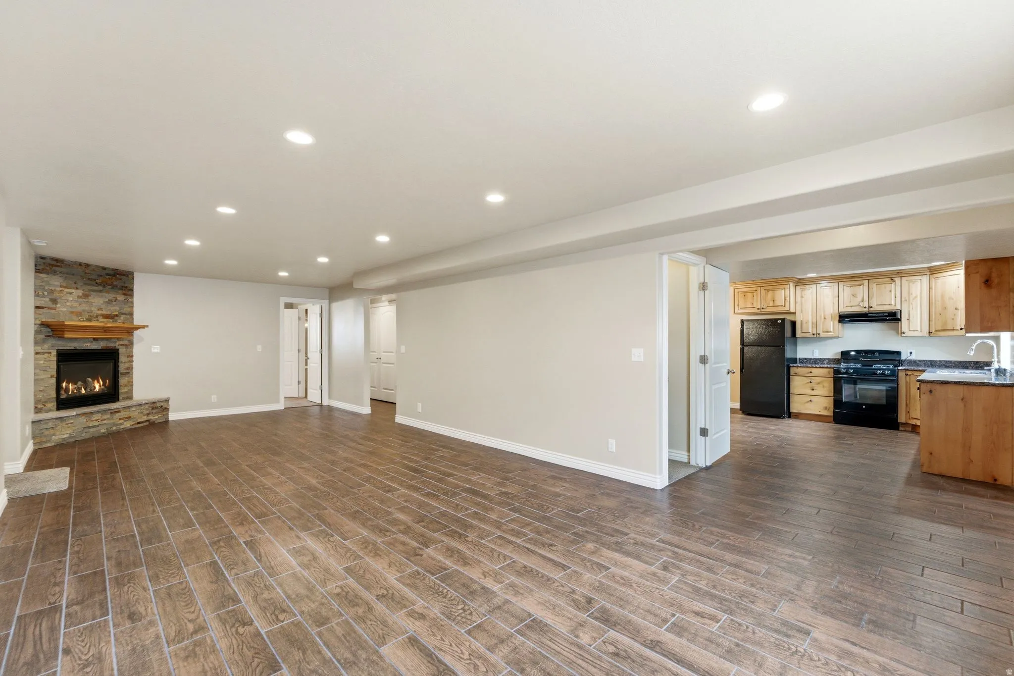 Unfurnished living room featuring recessed lighting, a stone fireplace, and wood tiled floors