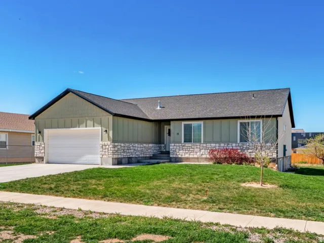 Ranch-style house featuring board and batten siding, driveway, an attached garage, stone siding, and a residential view