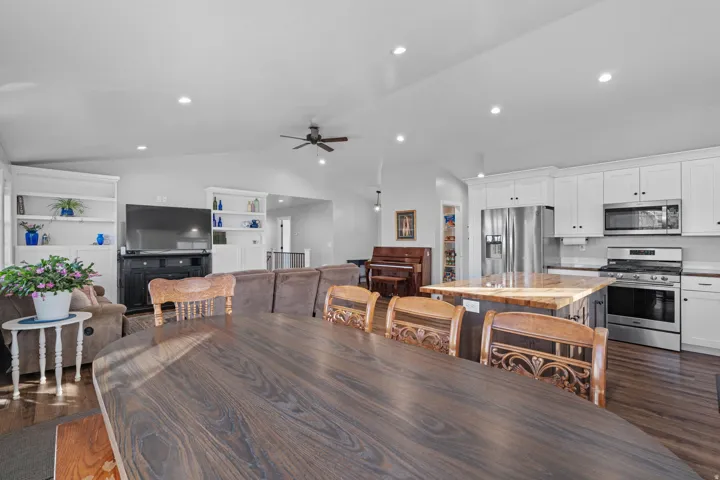 Dining area with dark wood-style floors, vaulted ceiling, built in shelves, recessed lighting, and a ceiling fan