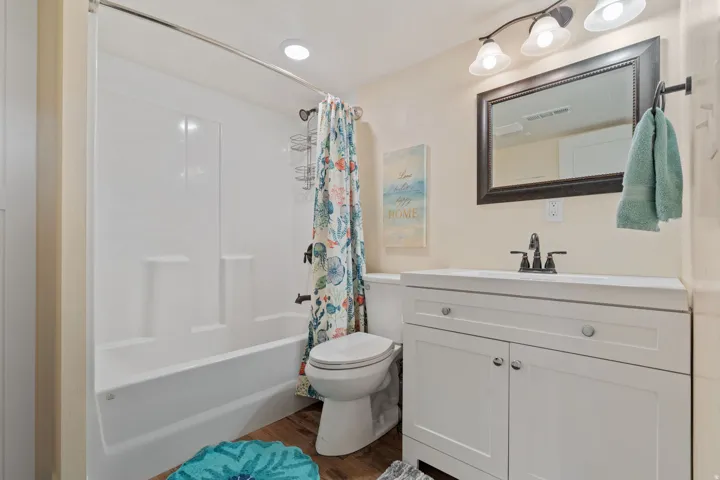 Bathroom with vanity, shower / bath combination with curtain, and dark wood finished floors