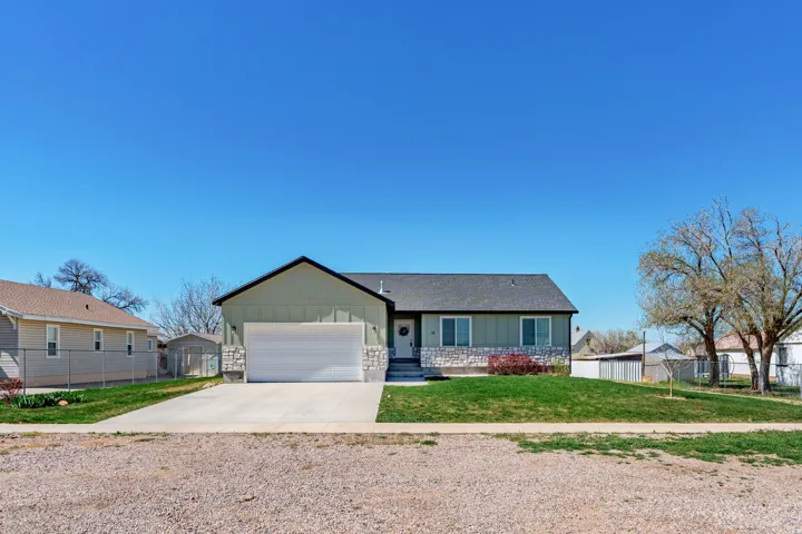 Single story home with board and batten siding, driveway, and a garage
