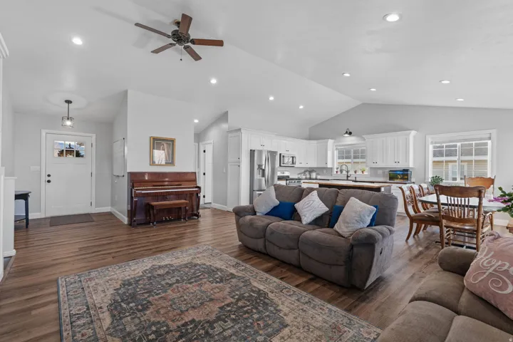 Living room featuring vaulted ceiling, dark wood-type flooring, ceiling fan, and recessed lighting