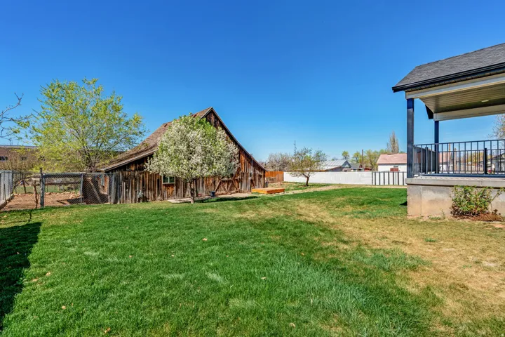 Fenced backyard featuring an outbuilding and a barn