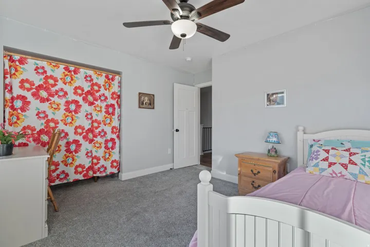 Carpeted bedroom featuring a ceiling fan and baseboards