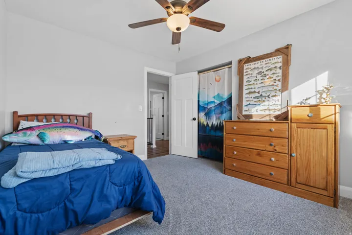 Carpeted bedroom with a ceiling fan