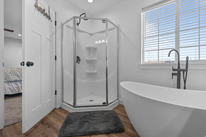 Ensuite bathroom with a shower stall, a freestanding bath, dark wood-style floors, and recessed lighting
