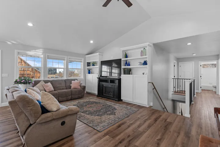 Living area with vaulted ceiling, wood finished floors, healthy amount of natural light, recessed lighting, and a ceiling fan