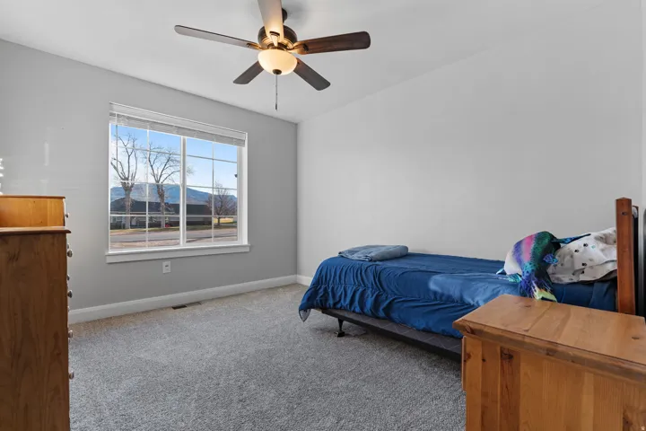 Carpeted bedroom with ceiling fan and a mountain view