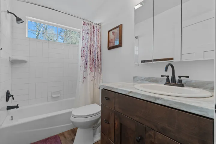 Full bath featuring shower / tub combo, vanity, and dark wood finished floors