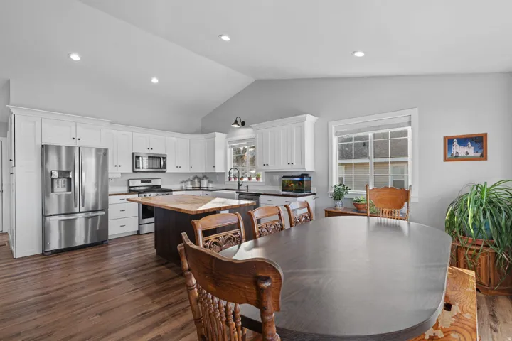 Dining room featuring dark wood-style floors, vaulted ceiling, and recessed lighting