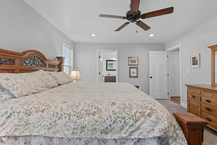 Bedroom with carpet flooring, ensuite bathroom, ceiling fan, and recessed lighting