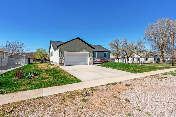 Ranch-style house featuring board and batten siding, driveway, an attached garage, and a residential view