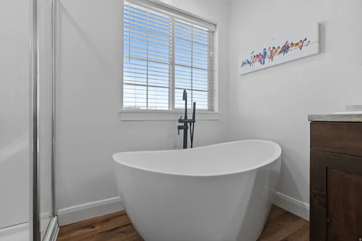 Bathroom with a soaking tub, dark wood-style flooring, and vanity