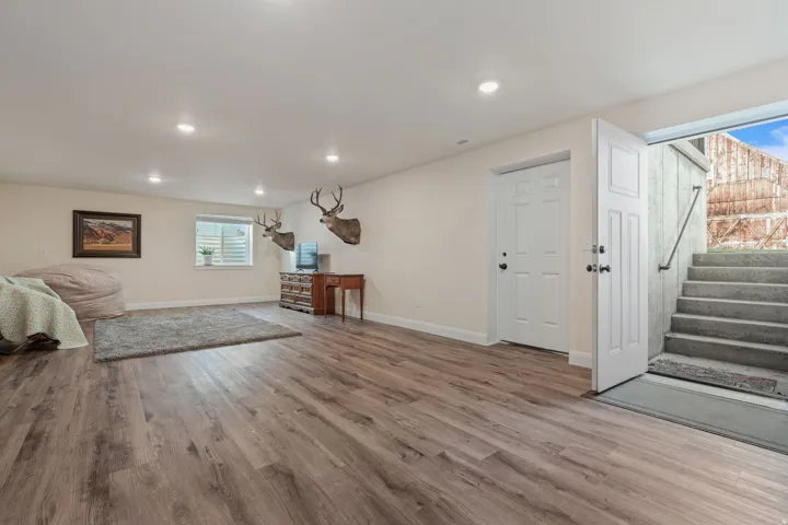 Family room with healthy amount of natural light, light wood finished floors, and stairway leading to back yard